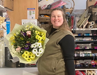 Florist proudly presenting a freshly arranged bouquet inside the workshop