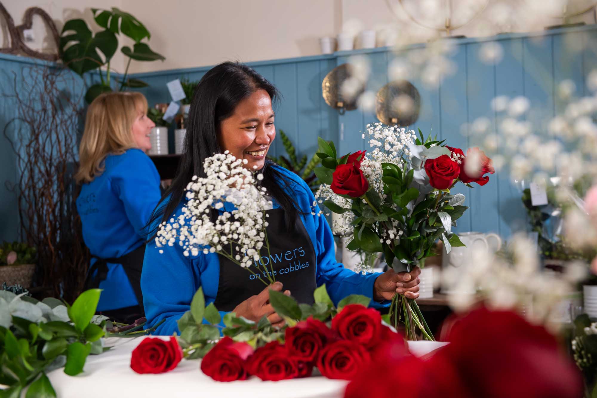 Smiling florist arranges red roses ready for delivery in ireland