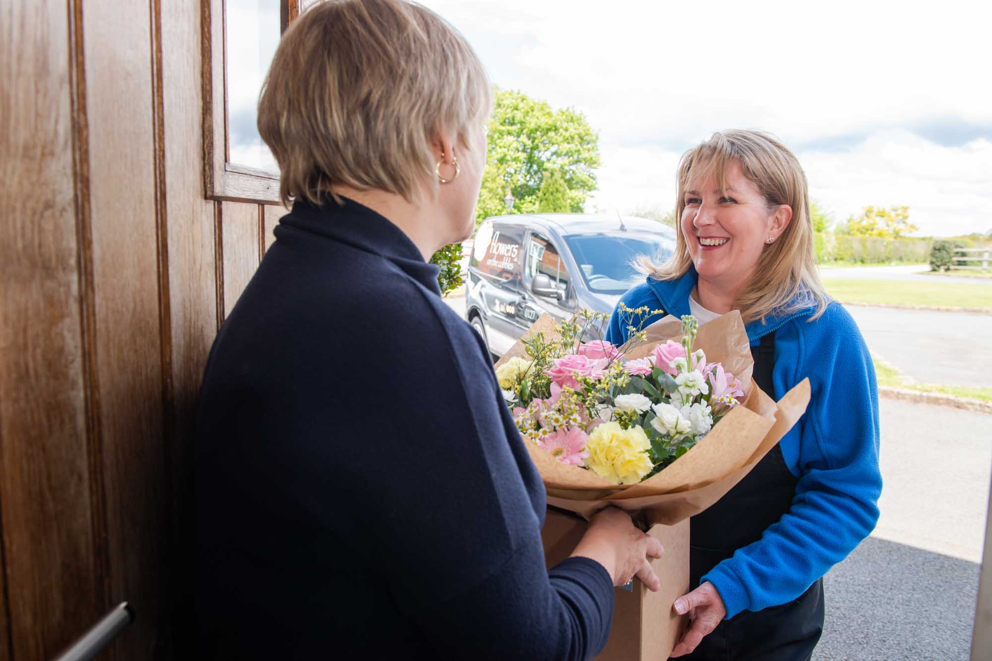 Florist delivering hand-tied bouquet to a woman at her front door