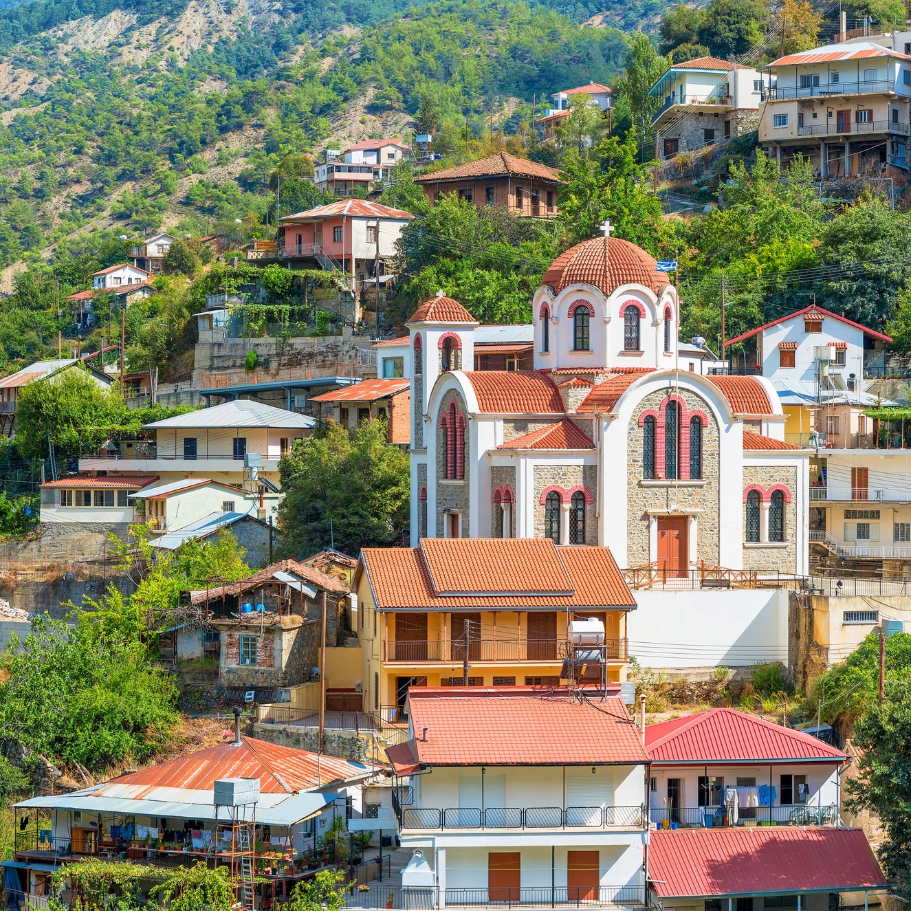 Hillside village in Nicosia, Cyprus, with a red-domed church and traditional homes.