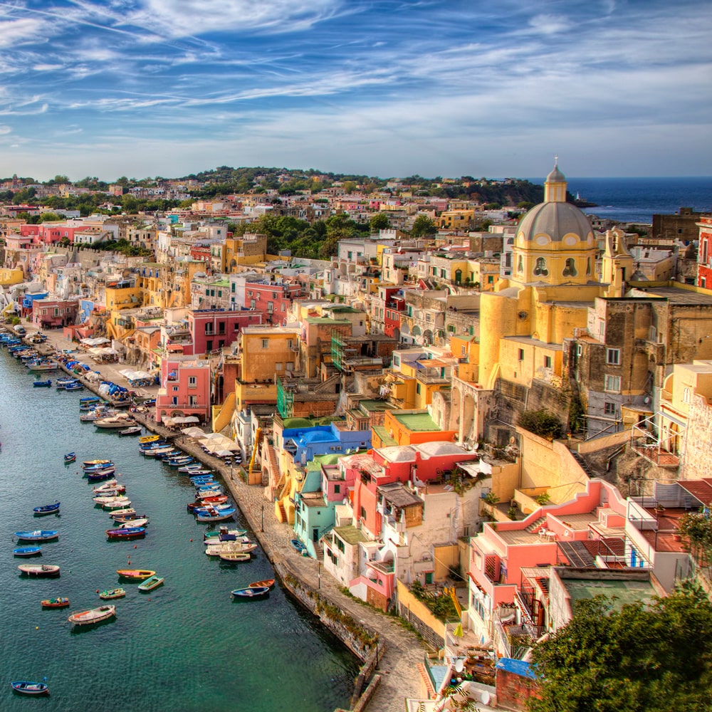 Colourful waterfront village near Naples, Italy, with boats docked along the coast.