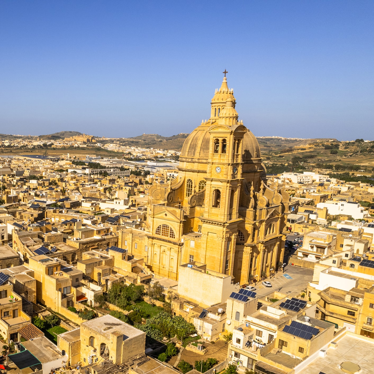 Gozo's skyline in Malta, featuring a grand church surrounded by traditional limestone buildings.