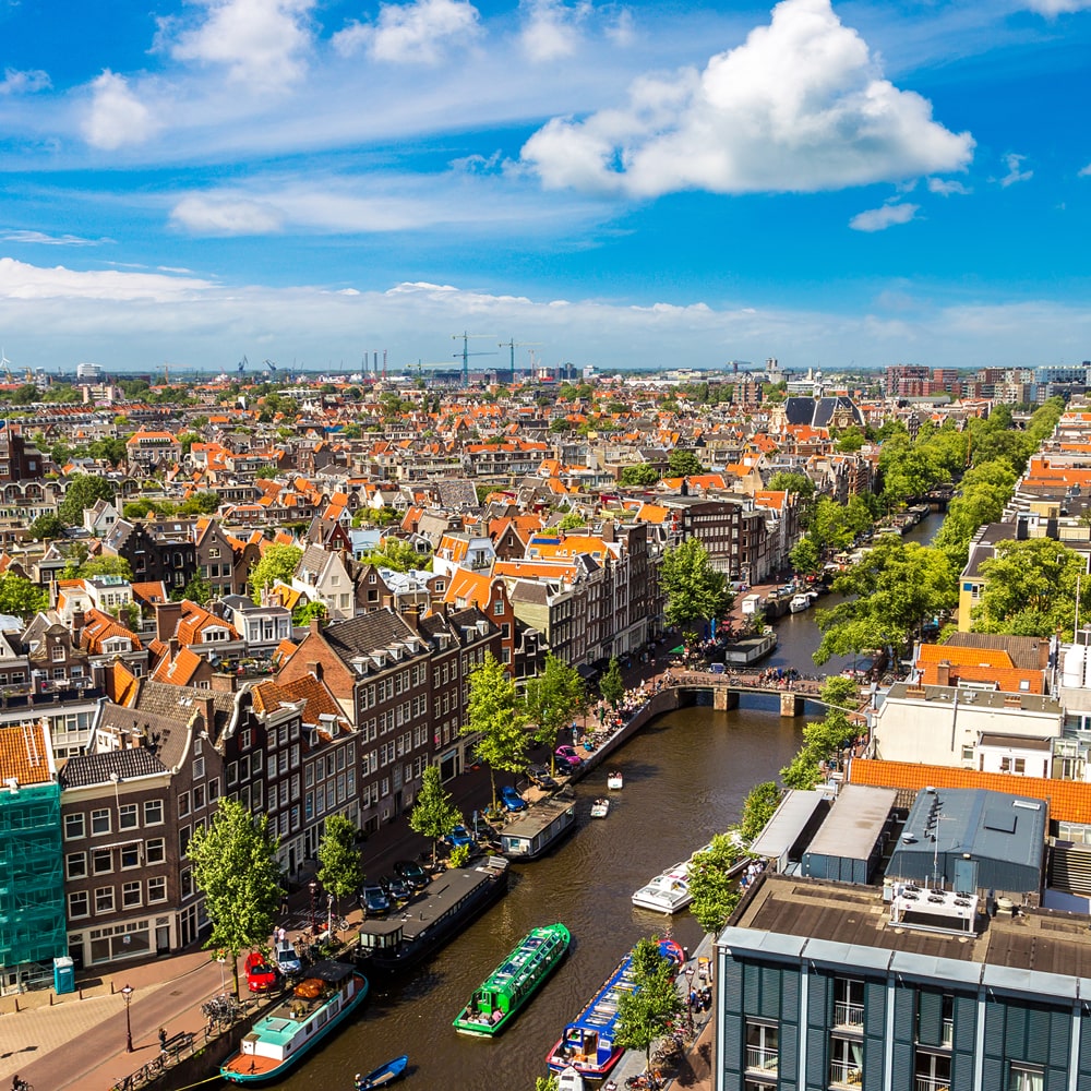 Amsterdam skyline with canals, bridges, and historic Dutch houses.