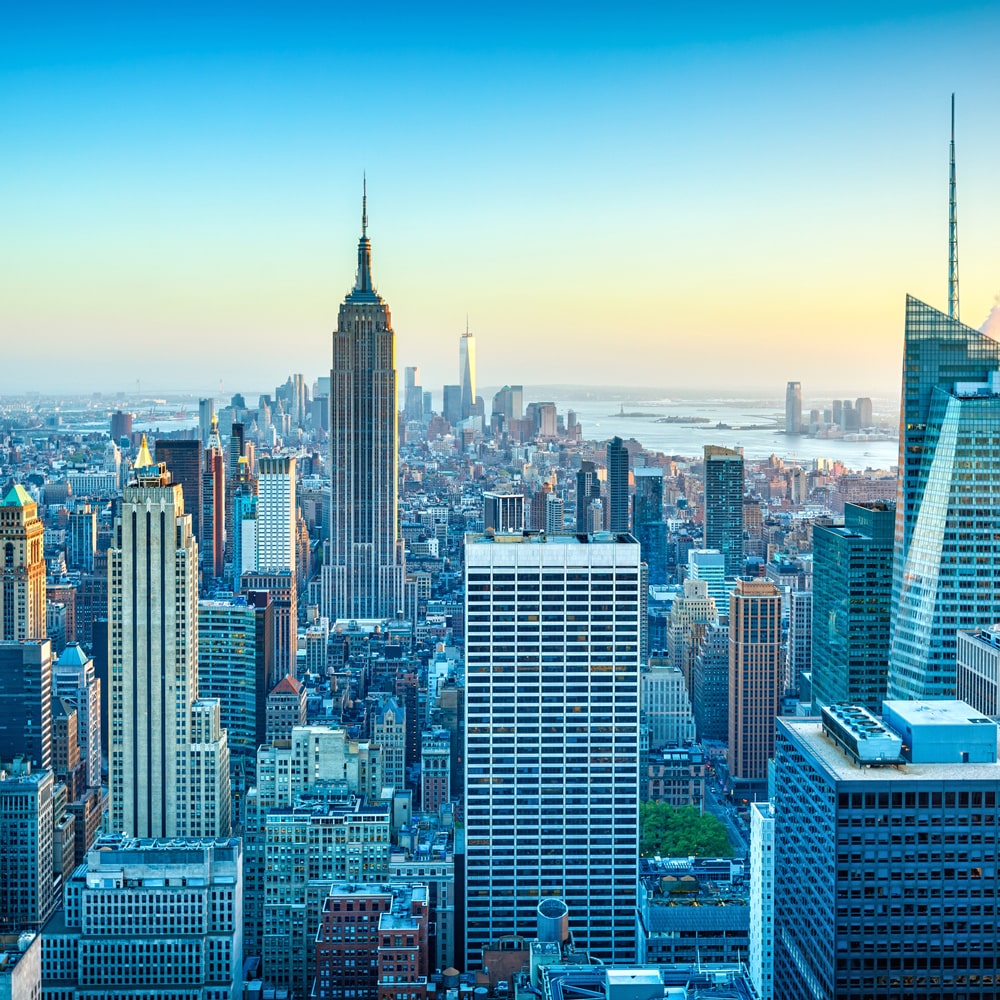 New York City skyline at sunset with the Empire State Building and surrounding skyscrapers.