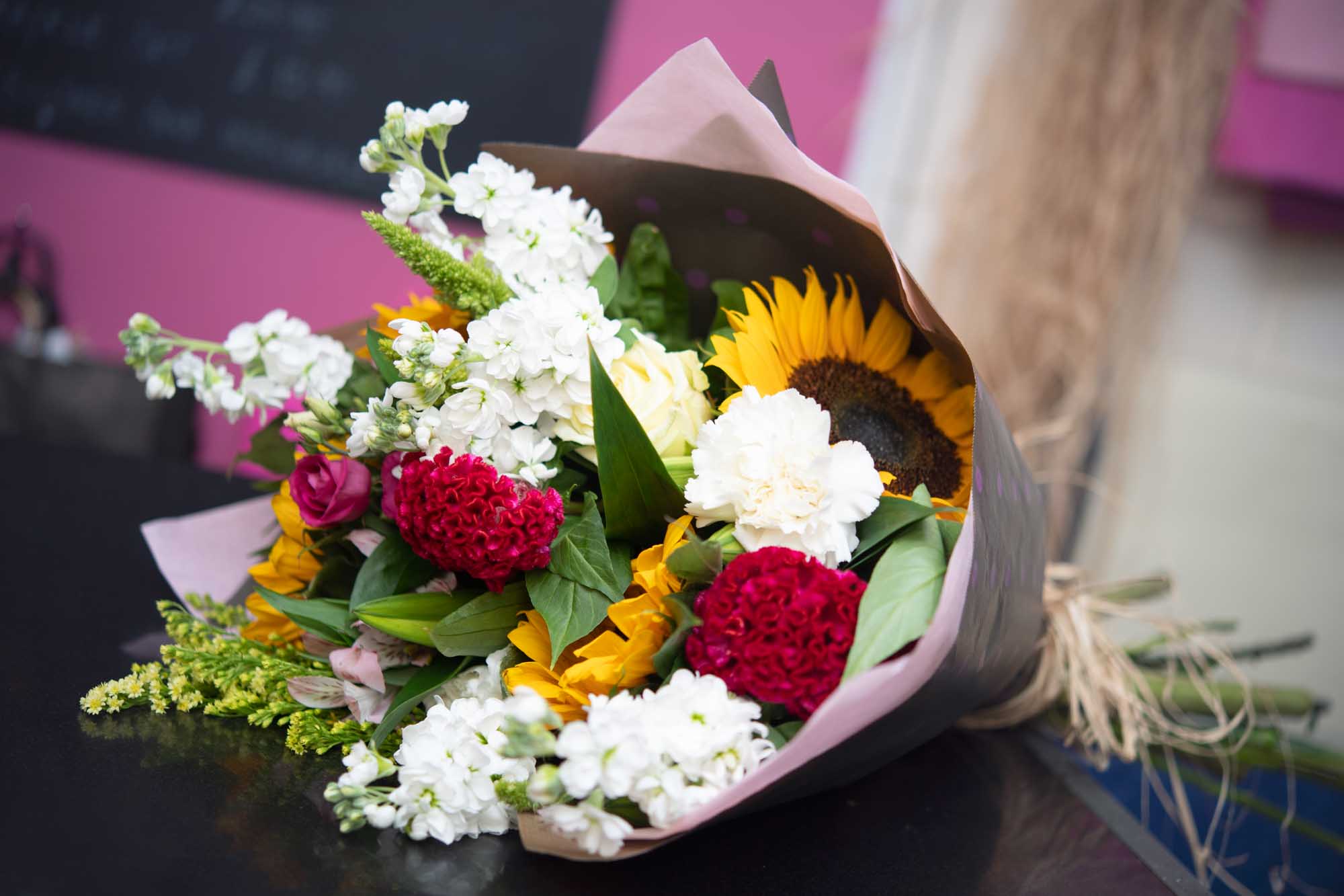 Brown eco-wrap of vibrant flowers layed on table featuring sunflowers and white white snapdragons