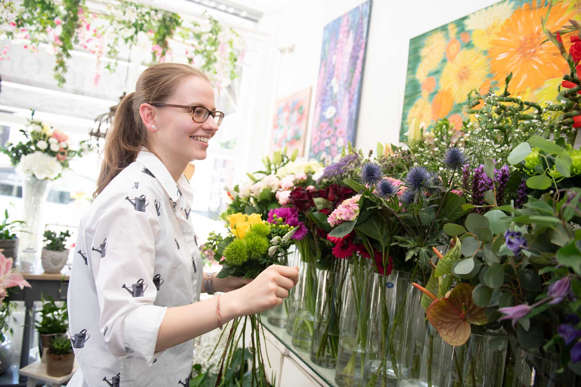 Florist is flower shop wearing white shirt choosing from a vibrant selection of flowers