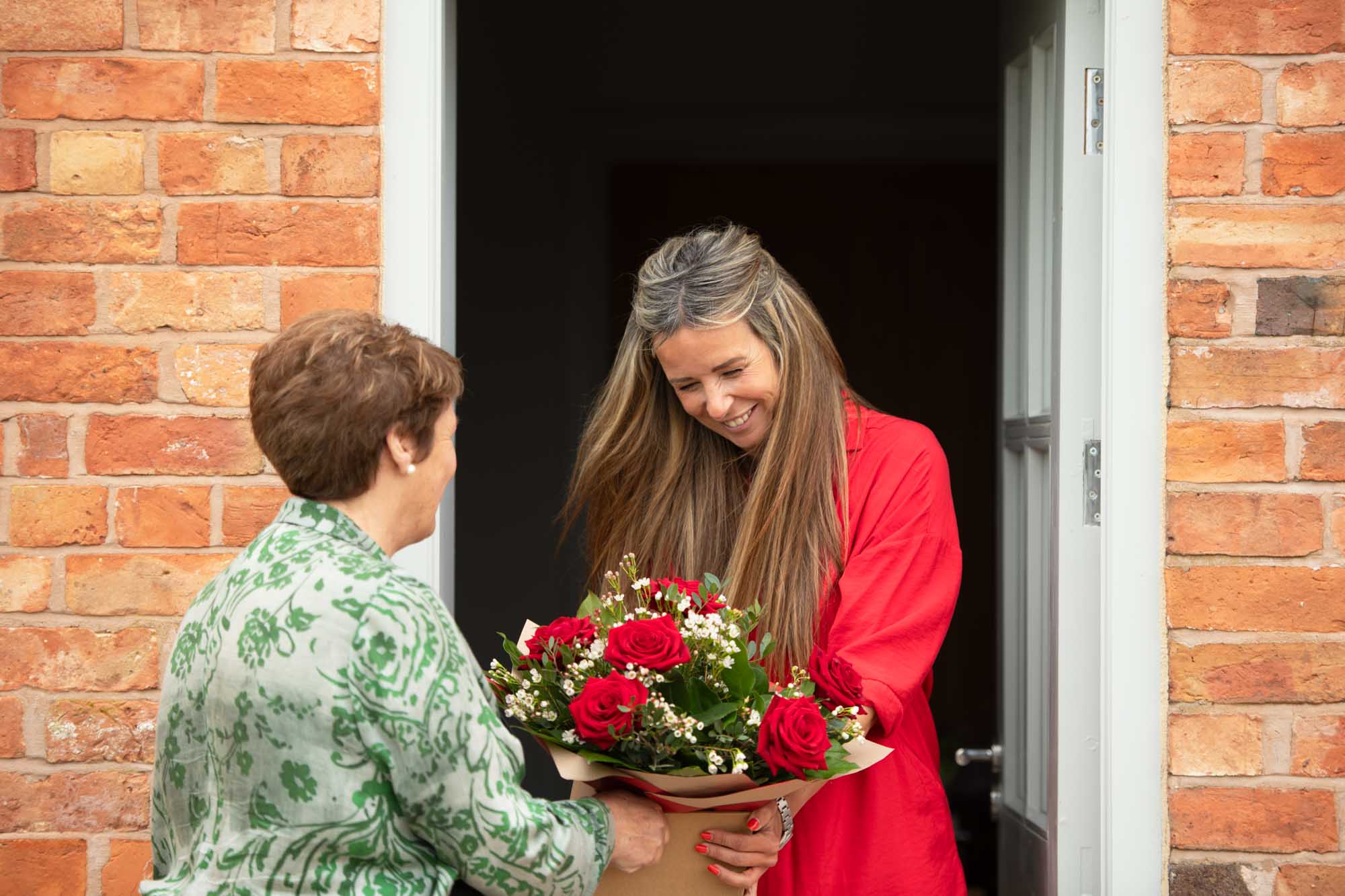 Florist delivers flowers to beautiful young lady at the door.