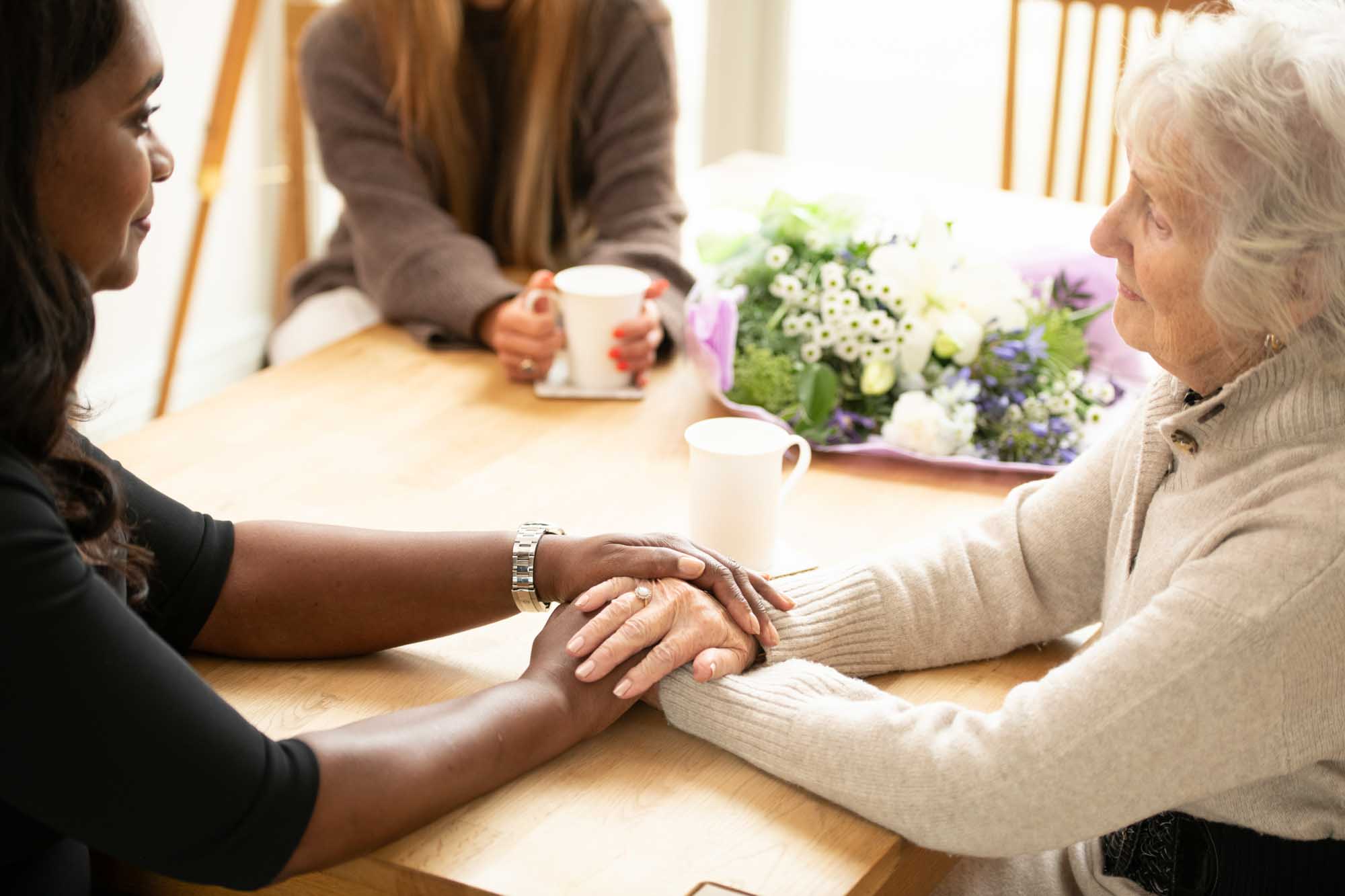 Friends holding hands at dining table while offering condolences