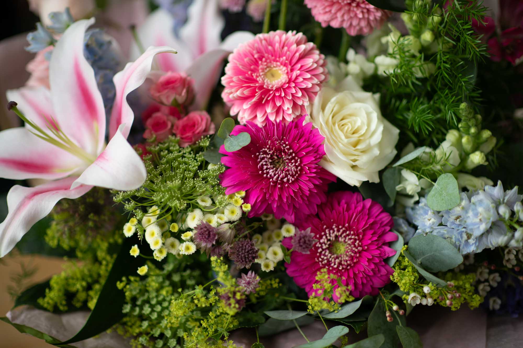 Close-up of a luxury vibrant hand-tied featuring oriental lilies, cream roses and gerberas