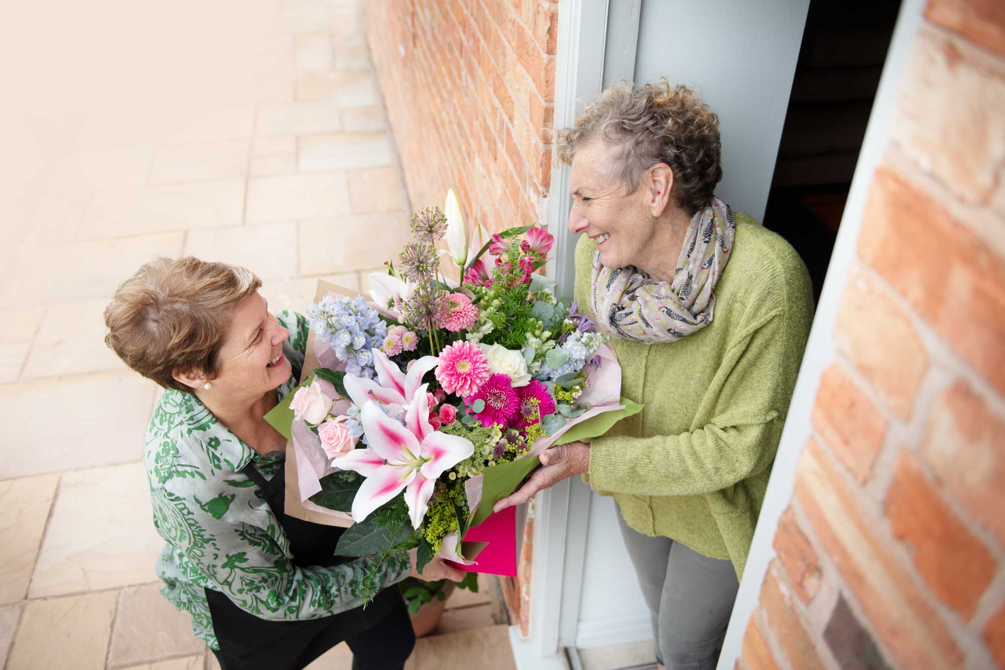 Luxury flowers in being delivered by a florist to a smiling woman at her door