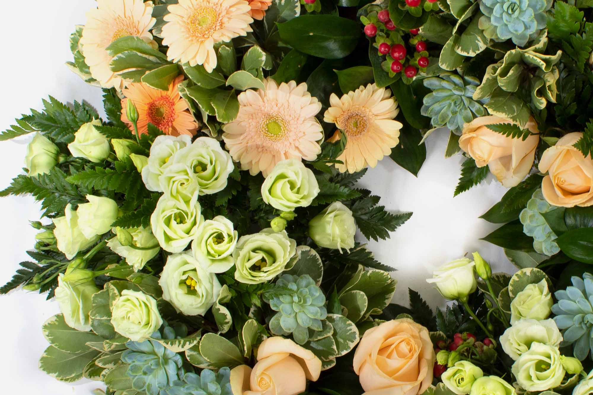 Close-up of a funeral wreath in peach theme on a white background