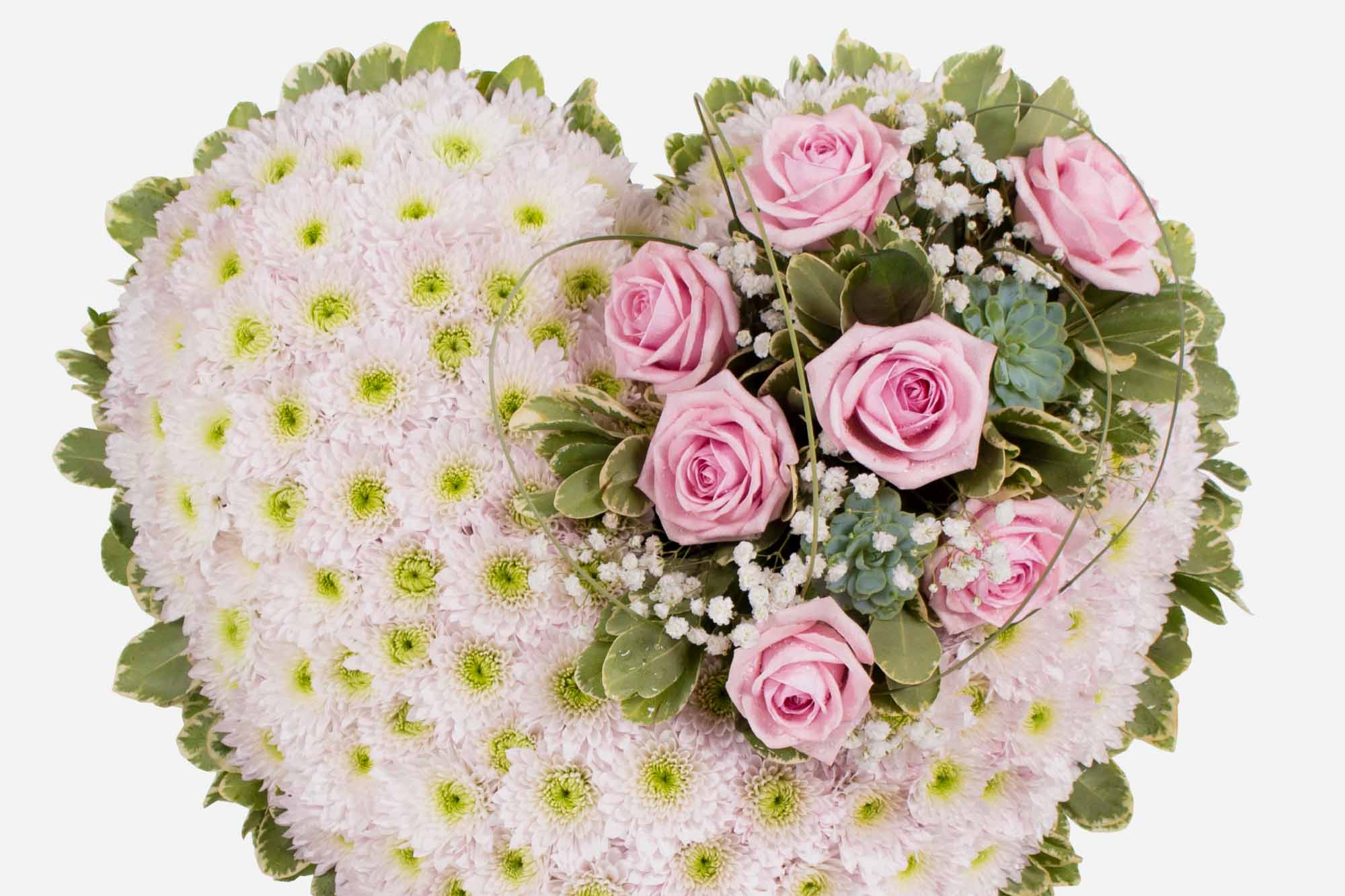 Close-up of a pastel pink funeral heart tribute on a white background