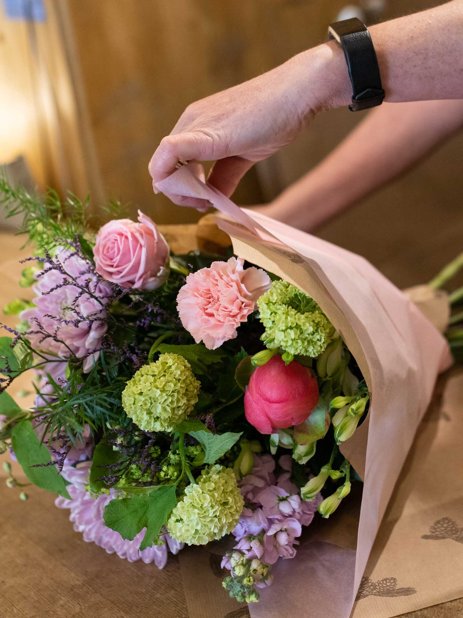 Hand of florist wrapping pastel and lilac themed bouquet