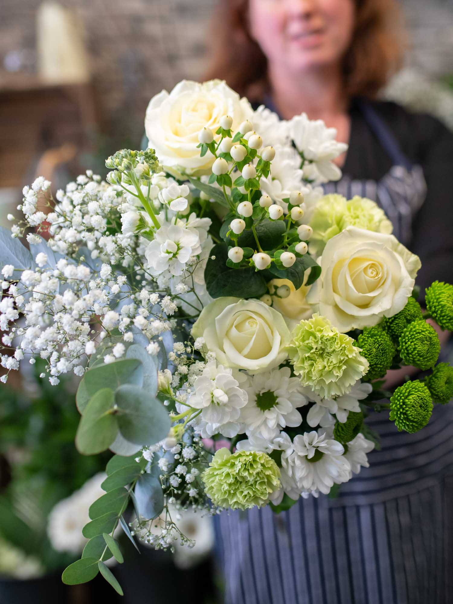 Florist holding a beautiful cream and white bouquet in front of her