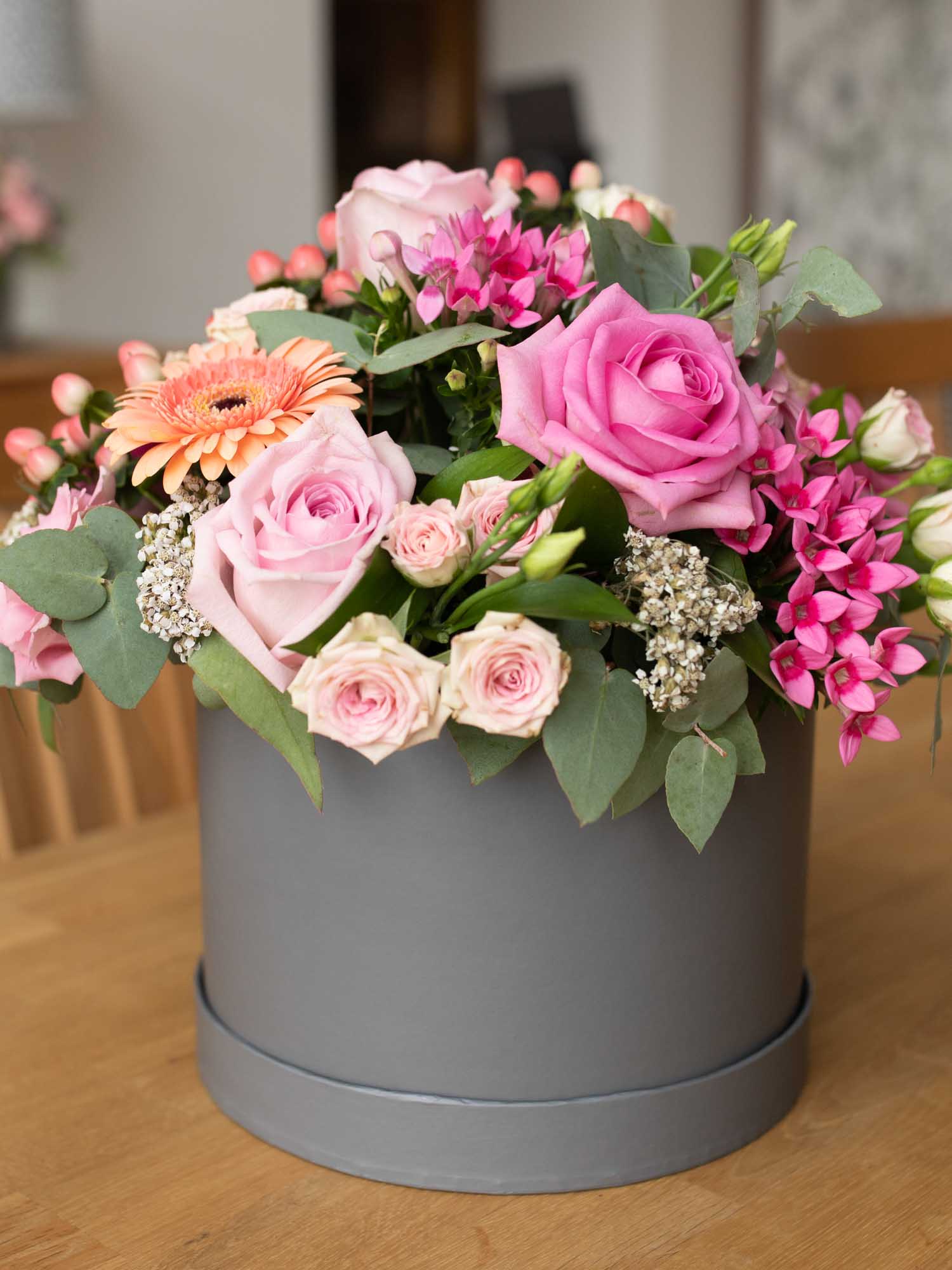 Close up of pink and peach flowers arranged in a hat box.