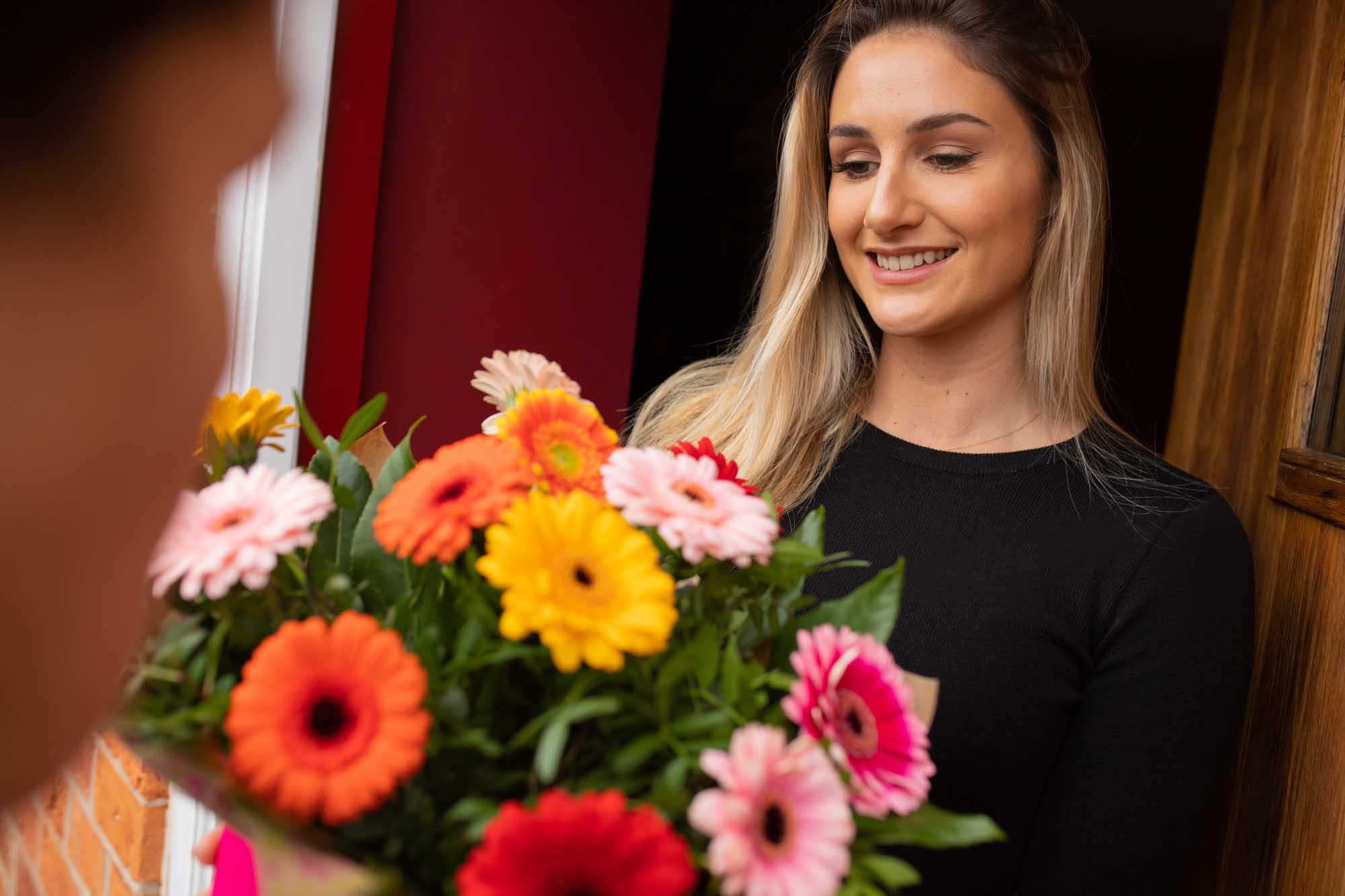 Young woman smiling and looking at the vibrant flowers being delivered to her