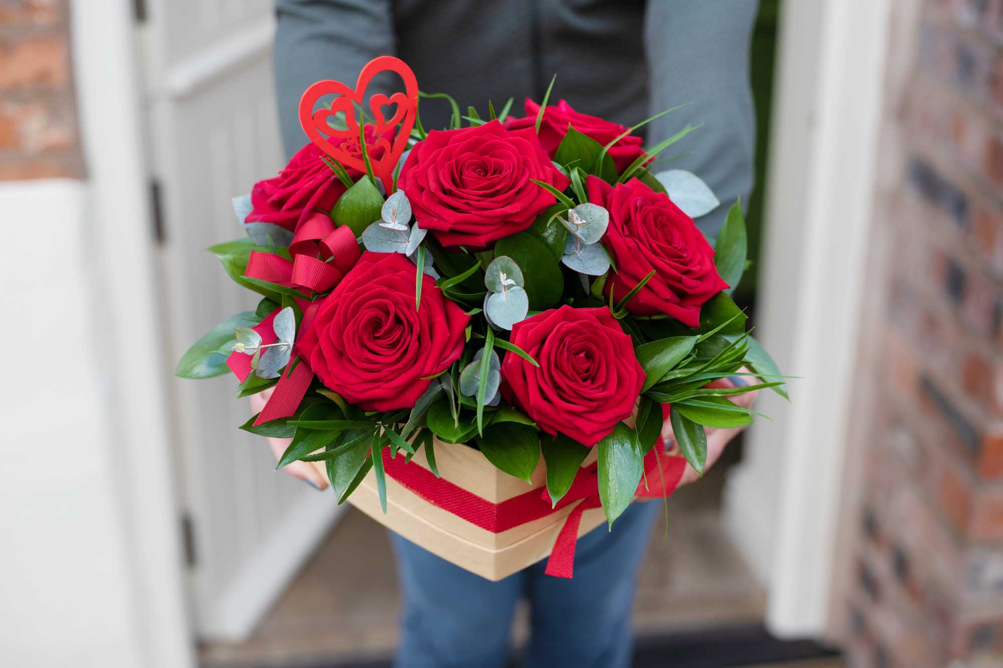 Young woman smiling receiving a Valentine's day bouquet of a dozen red roses.