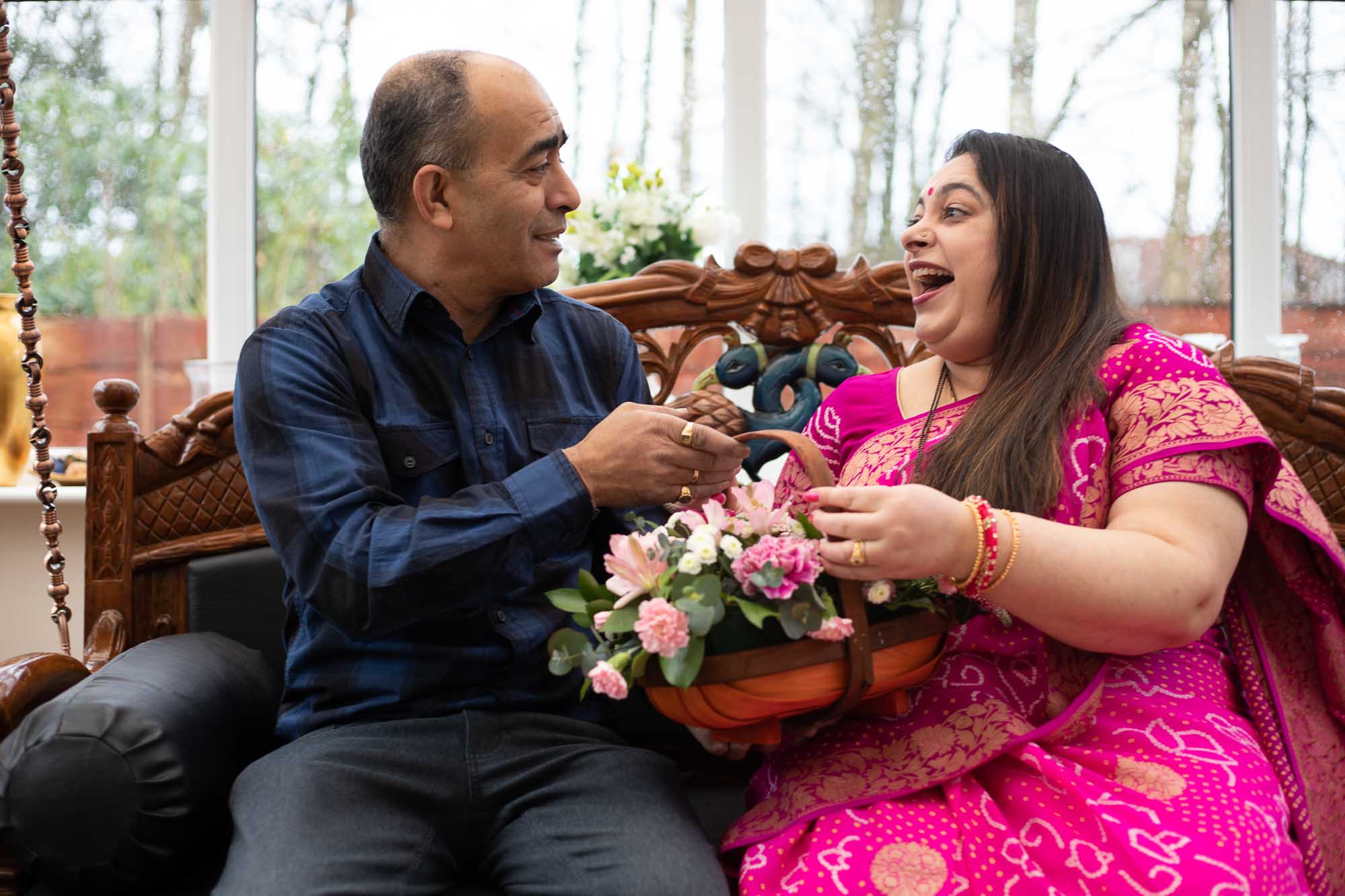 Happy Indian husband and wife enjoying a playful moment with basket of flowers