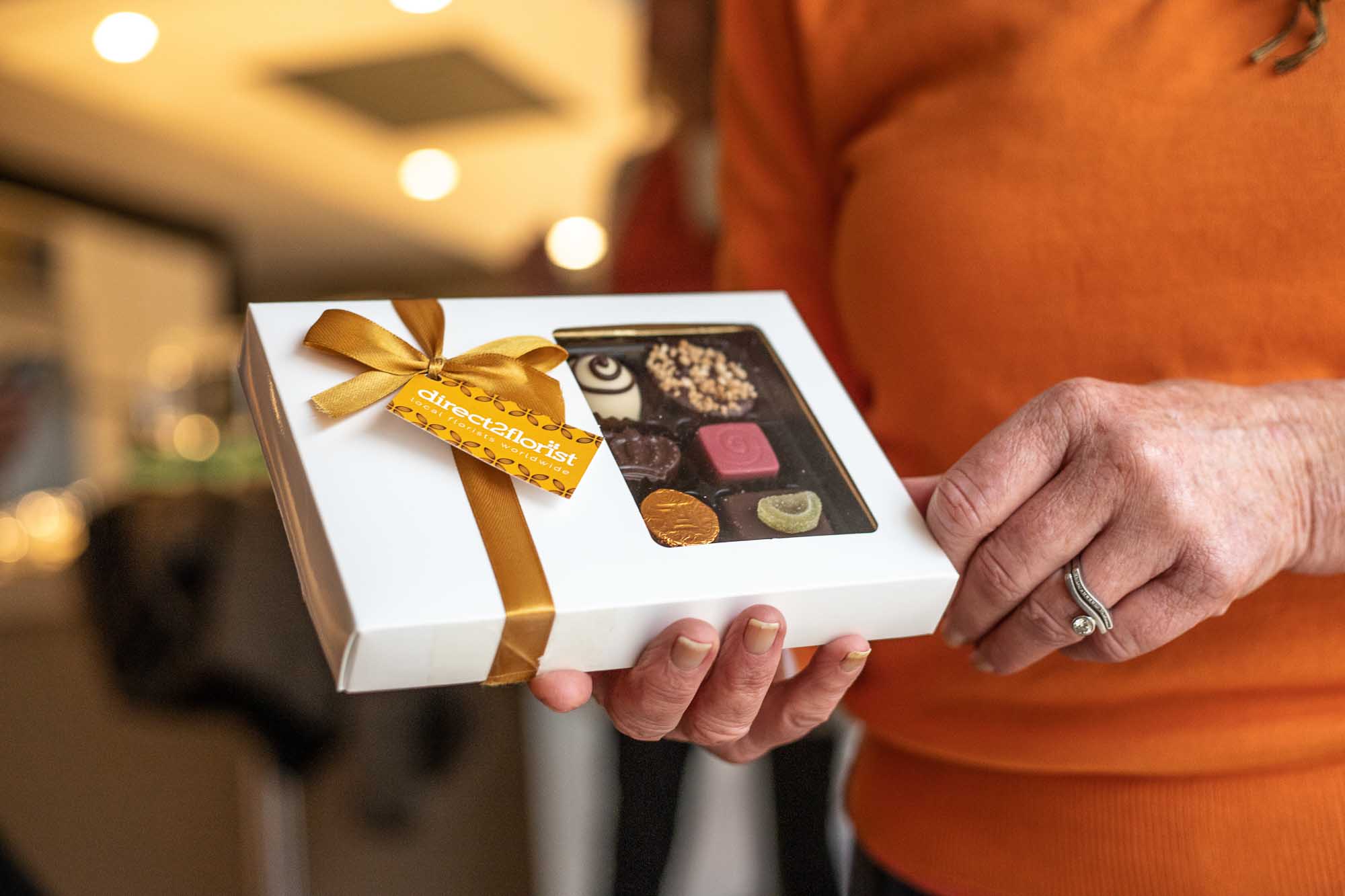 Close up of a hand holding Direct2florist branded chocolates