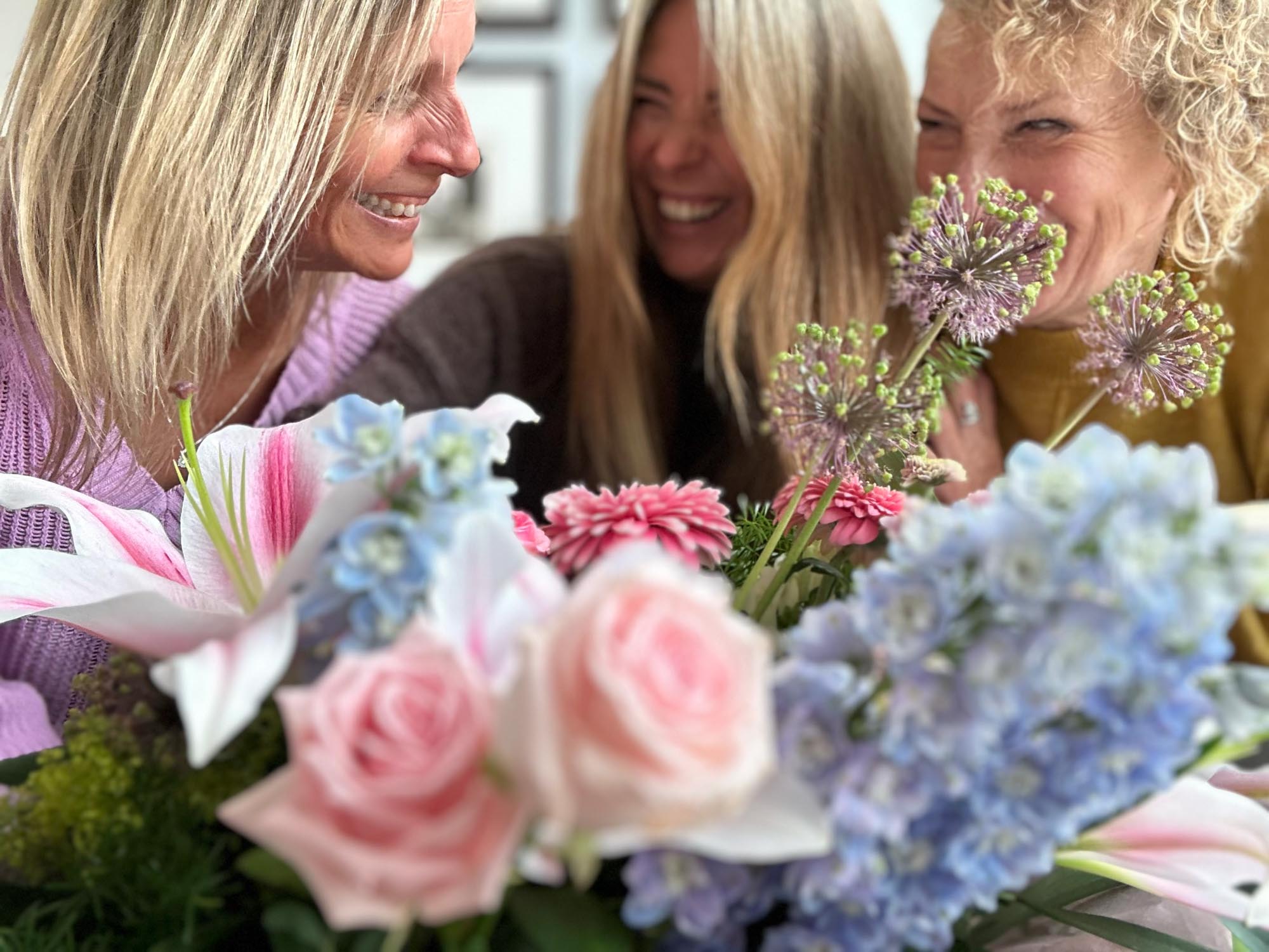 group of 3 friends laughing and enjoying each others company with a featured close up of flowers